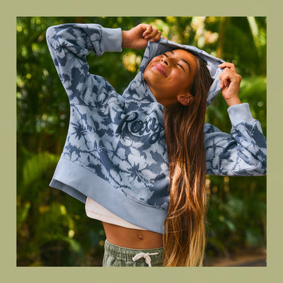 Person wearing a blue tie-dye hoodie with Roxy branding, standing outdoors with greenery in the background.