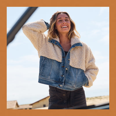 Woman wearing a denim jacket with a cream sherpa lining outdoors