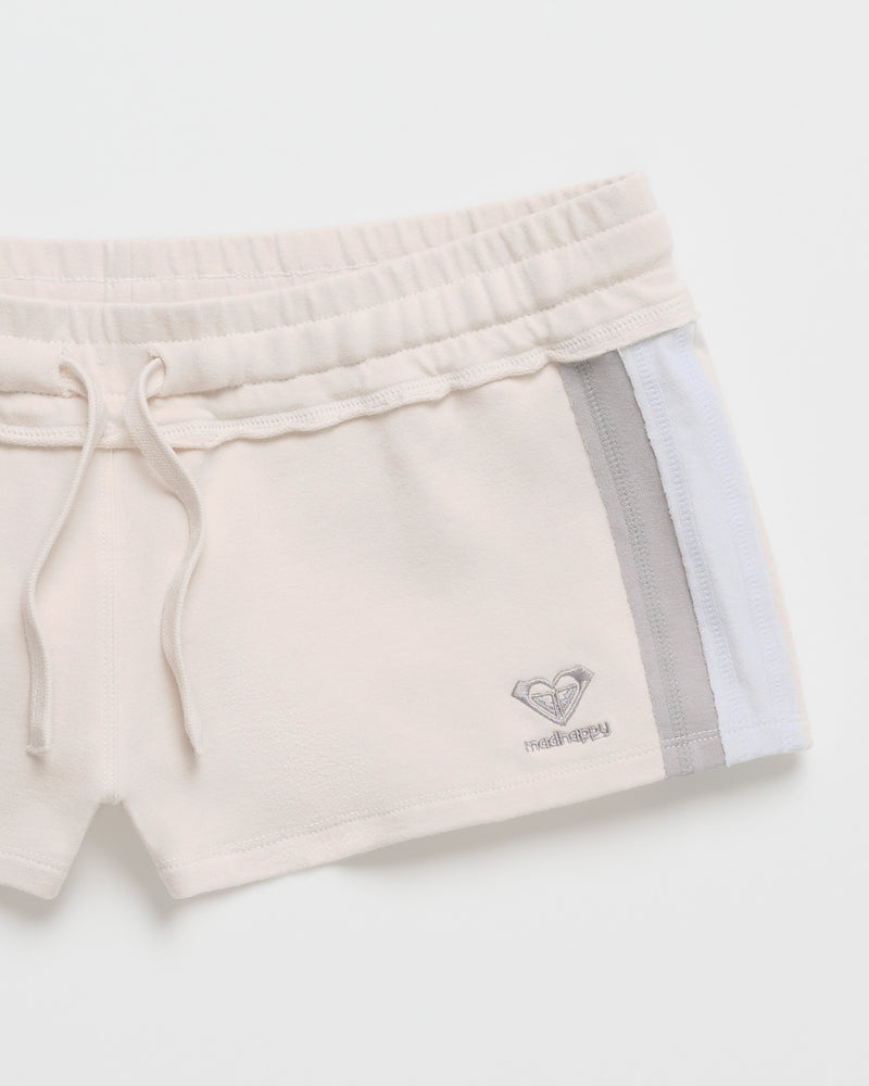 The ROXY x Madhappy French Terry Mini Short features a chic Birch finish and is crafted from soft French Terry for optimal comfort. These beige athletic shorts are designed with an elastic waistband, adjustable drawstring, and white and gray side stripes. An embroidered heart-shaped logo with "maliimopi" detail accents the bottom hem, channeling the signature style of the Roxy x Madhappy collaboration.