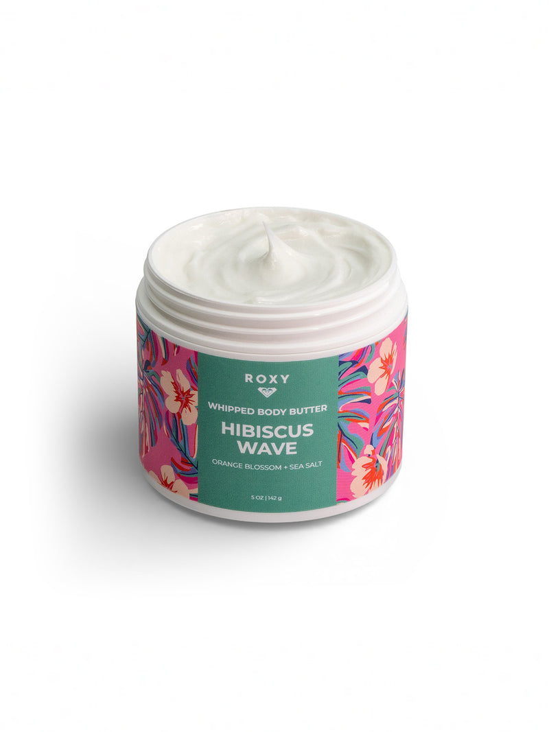 An open jar of Roxy Hibiscus Wave Body Butter displays its creamy white formula, with a pink, orange, and blue tropical floral label. This hydrating lotion soothes dry skin and locks in moisture after your shower.
