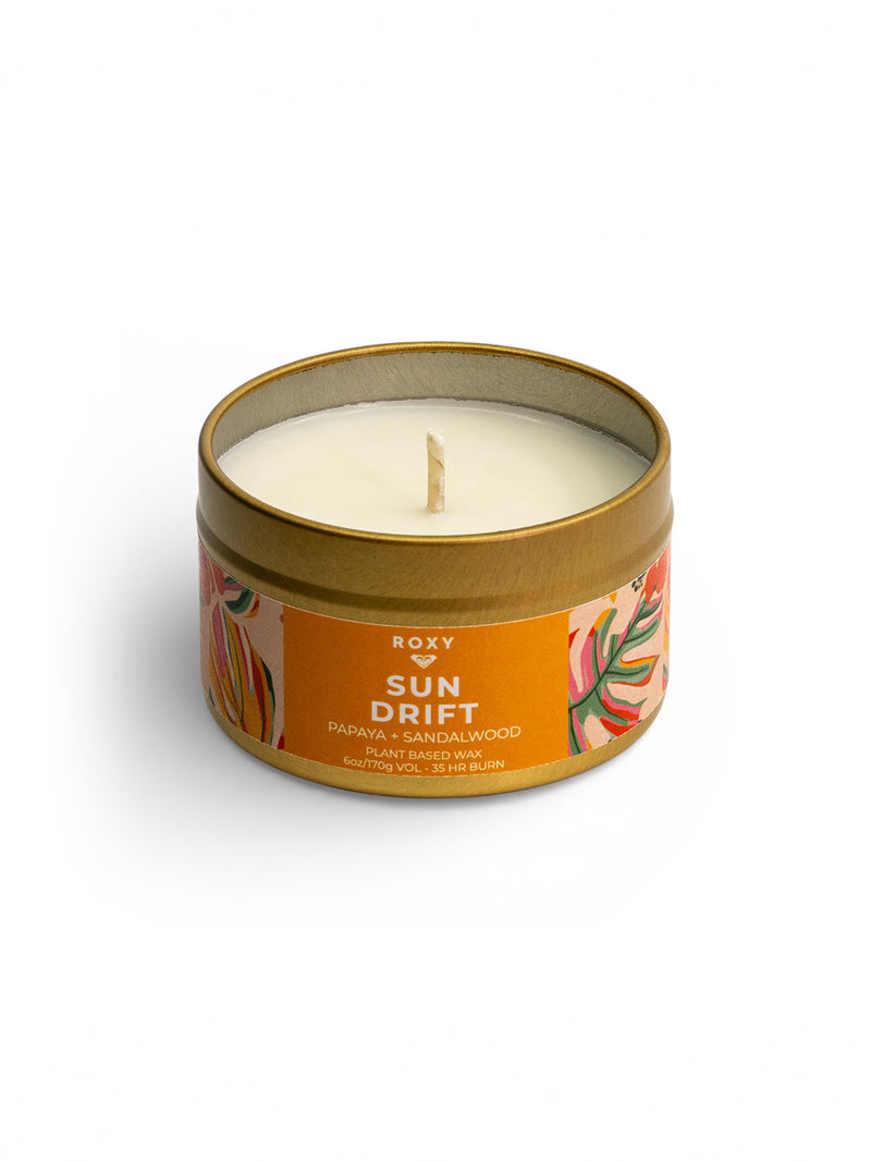 A small round tin beach candle from Roxy called Sun Drift Palm, featuring a single wick and colorful label. Enjoy a tropical scent, soy blend wax, and up to 33 hours of burn time.