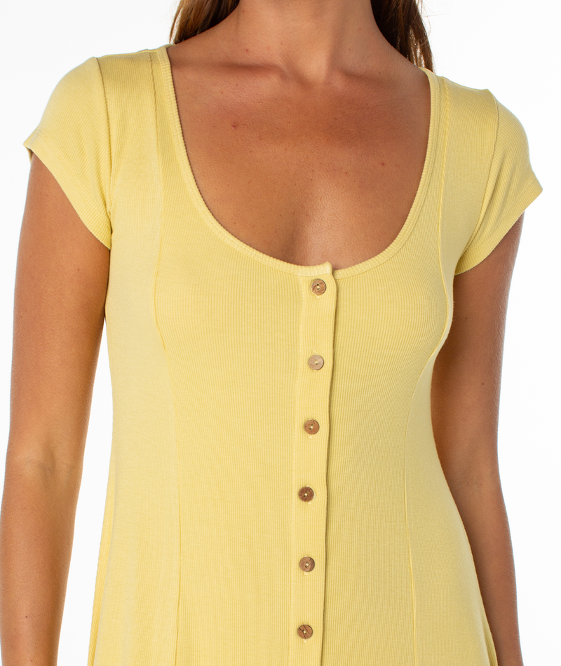 A woman wears the Roxy Sea Breeze Mini Dress, a yellow short-sleeved, scoop-neck style with front buttons, shown from shoulders to hips against a white background for effortless coastal cool.