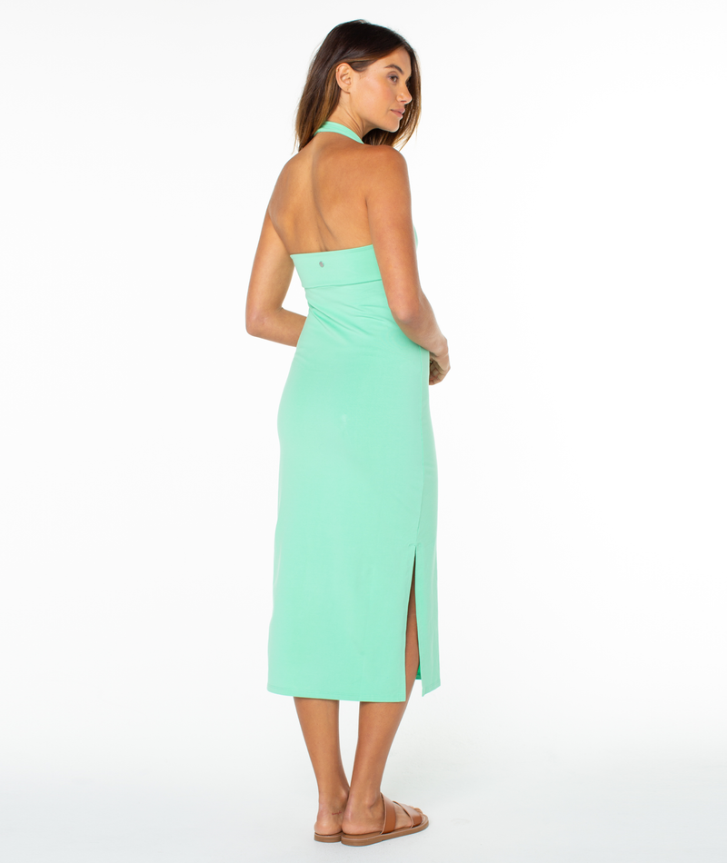A person viewed from behind wearing a mint green South Shore Midi Dress with a side slit and tan sandals.