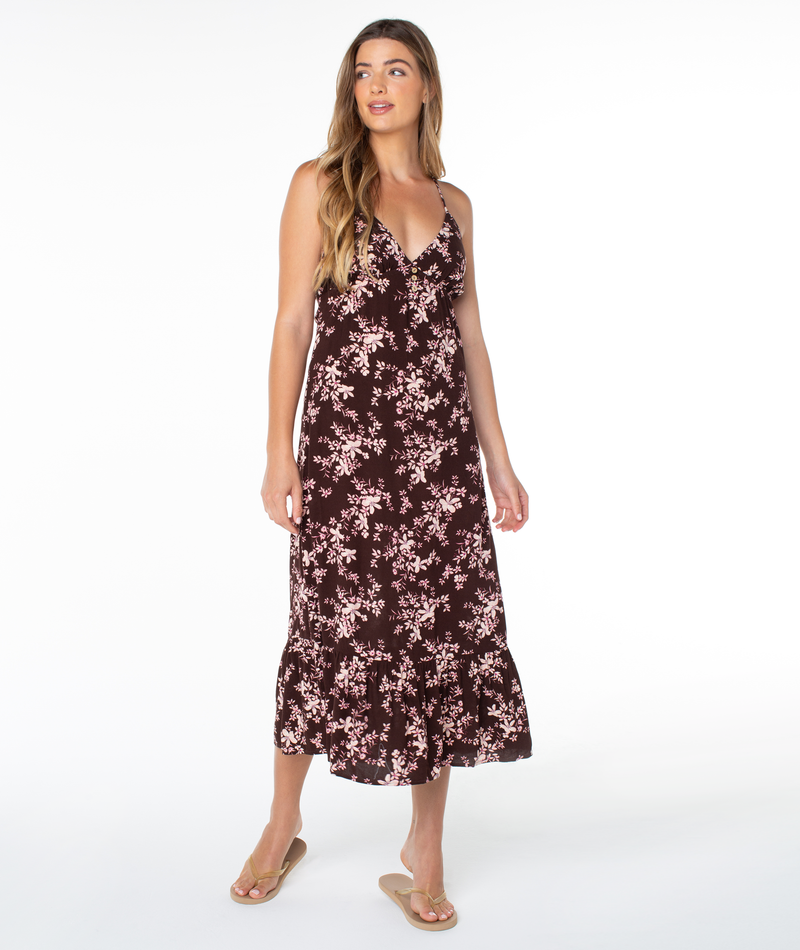 Woman in the Roxy Warm Rays Midi Dress in Tulipwood Evening Meadow, featuring a sleeveless floral print and ruffled hem, stands against a white background with sandals.
