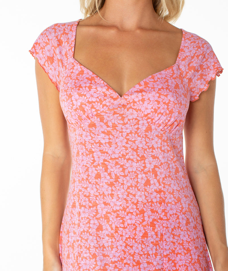 A woman wearing the Roxy Alice Mini Dress, featuring a floral print, sweetheart neckline, and short sleeves, shown from shoulders to mid-thigh against a white background—a true wardrobe staple.