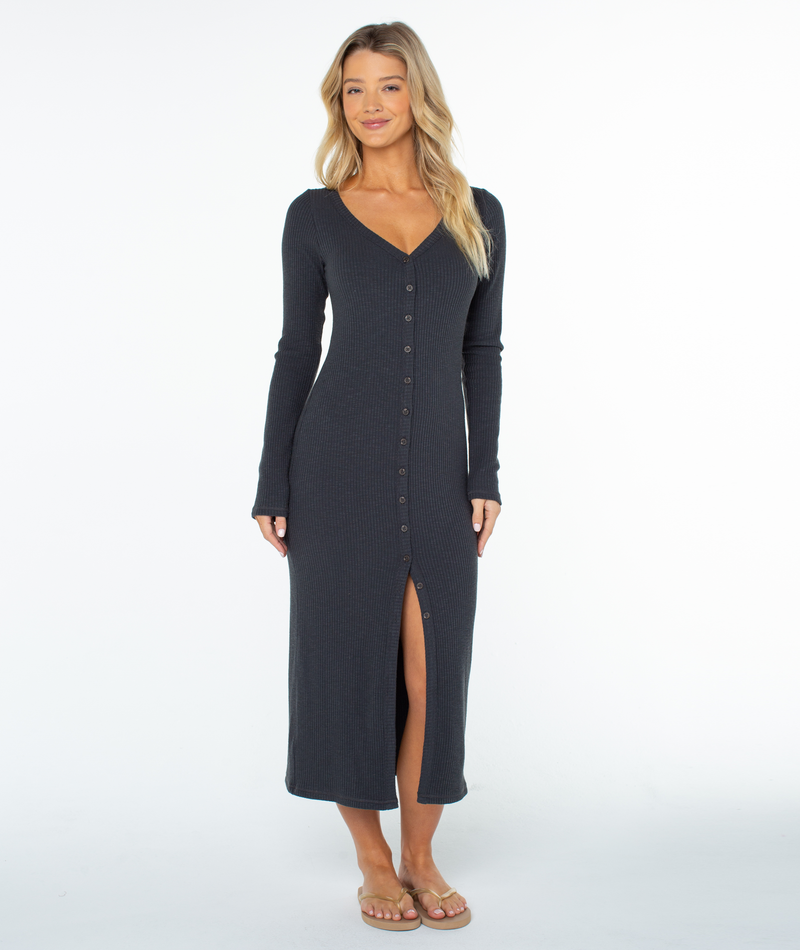 A woman wears a charcoal gray ribbed Roxy Terrace Dress, a winter maxi with a romantic silhouette, button-down front, and a high leg slit.