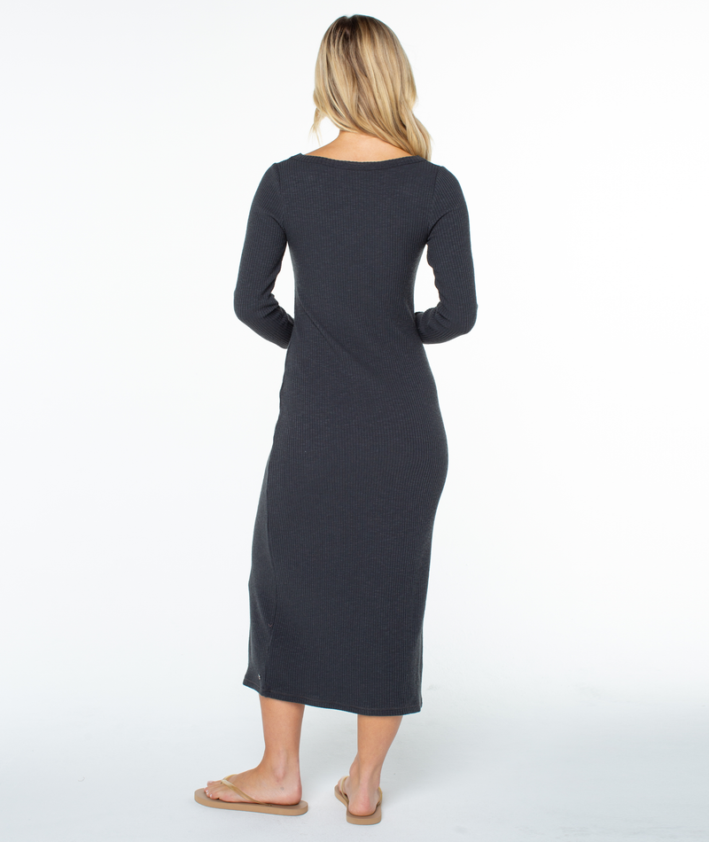 A person seen from behind, wearing a charcoal grey Roxy Terrace Dress and flip-flops, creating a romantic silhouette.
