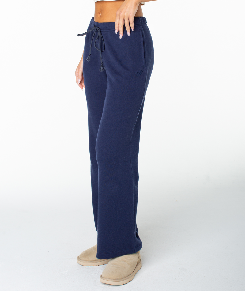 A person is wearing Roxy’s Good Times Pant in Naval Academy Solid, featuring a drawstring waist, paired with tan slippers. The image captures the body from the midriff down against a plain white background—perfectly complemented by the matching Dream Thing top.