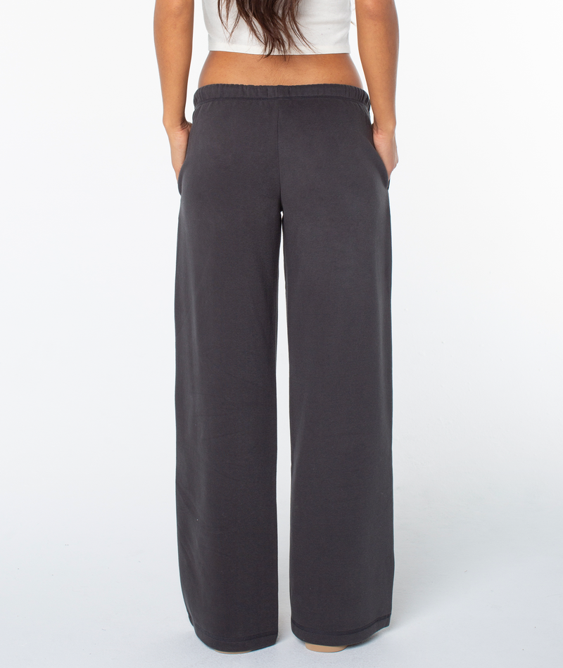A person wearing the Roxy Ariel Wide Leg Pant stands facing away with hands in their pockets, against a plain white background.