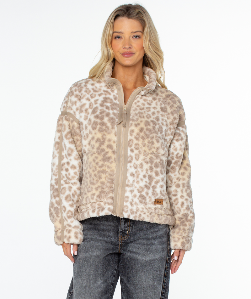 A person wearing a Roxy Wurlie Fleece Jacket, a coastal cool, zip-up style featuring a tan and cream leopard statement print.