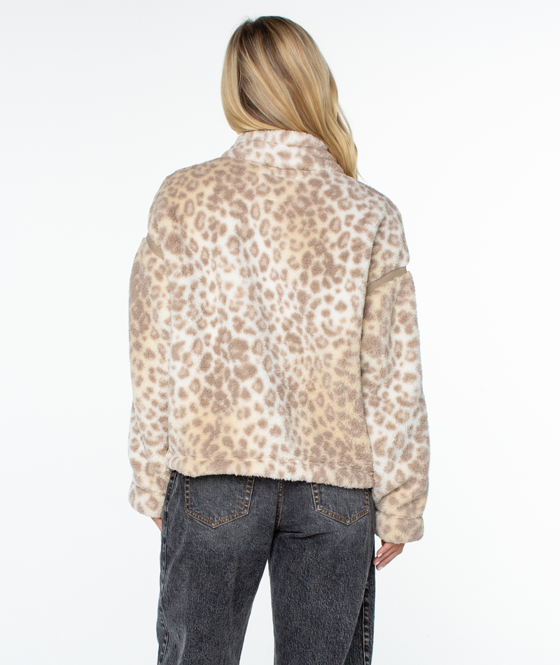 Back view of a person wearing a beige and brown leopard print Roxy Wurlie Fleece Jacket with a high collar and dark grey jeans, finished with a statement print for coastal cool style.