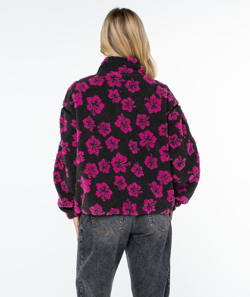 Person from behind wearing a black zip-up Roxy Wurlie Fleece Jacket with a statement pink floral print and dark gray jeans.
