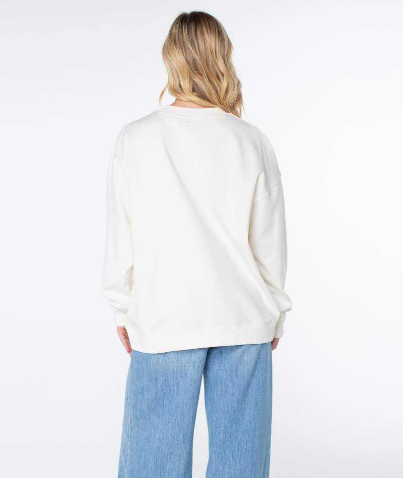 Back view of a person wearing a plain cream Roxy Line Up Crew Top and light-wash blue jeans for coastal comfort.