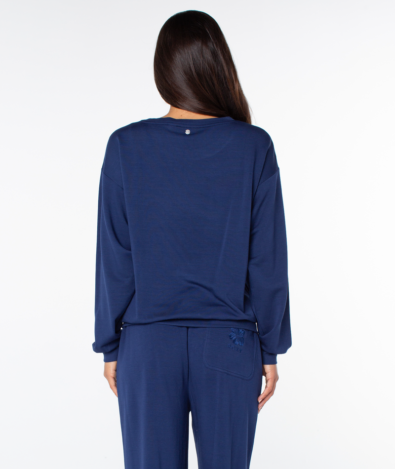 A woman seen from behind wearing a navy blue Roxy Surfing By Moonlight Top and matching pants.