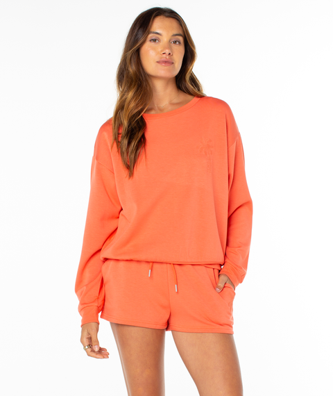 A woman with long brown hair wears the Roxy Surfing By Moonlight Top and matching shorts, posing against a plain white background with one hand in her pocket, looking ahead.