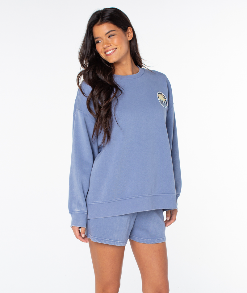 A woman with long dark hair wears the Roxy Hazy Daze Patch Top and matching shorts, standing against a white background, smiling and looking slightly to her right.