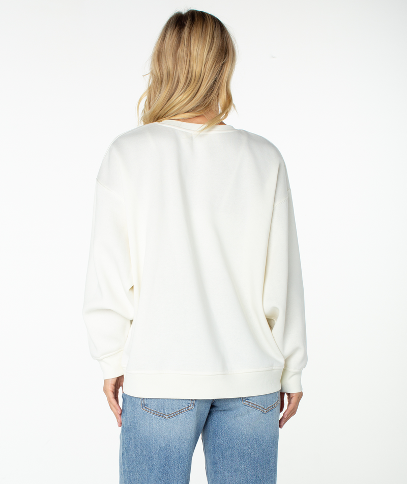 Back view of a person wearing a white Roxy Morning Stroll Top crewneck sweatshirt and blue jeans.