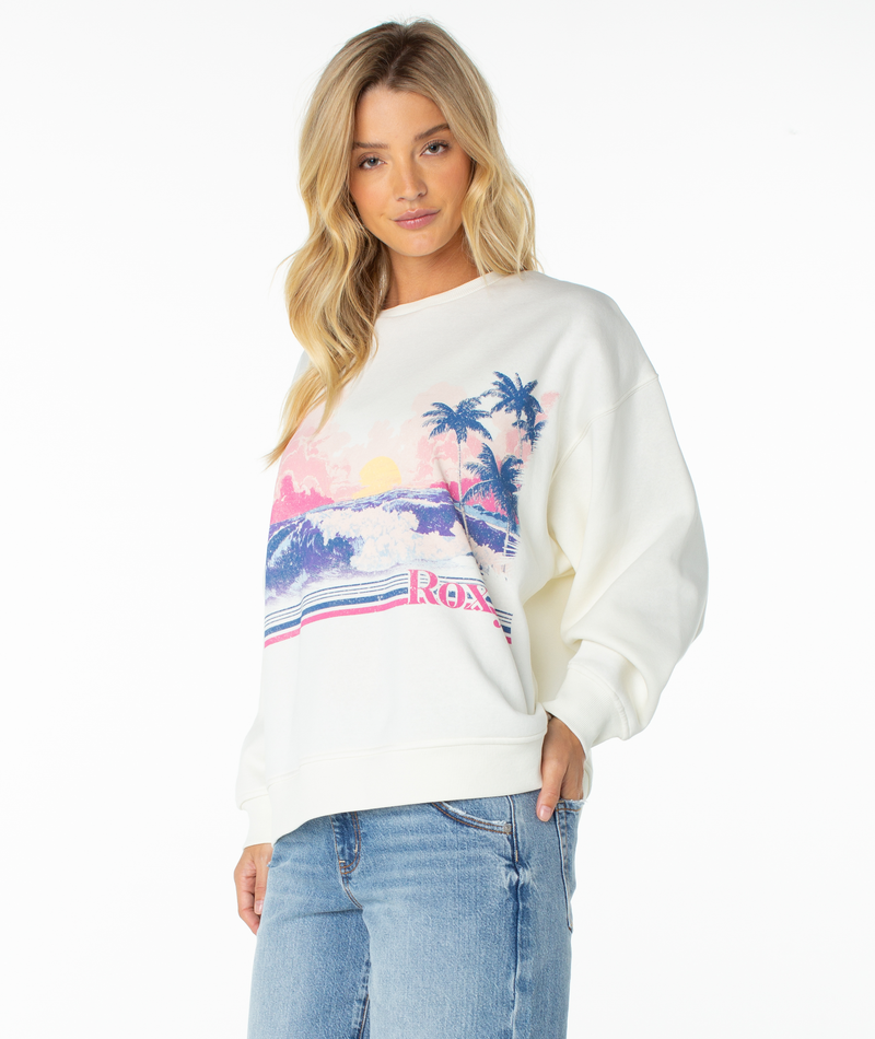 Woman wearing a cream-colored Roxy Morning Stroll Top with a graphic print of a beach scene including palm trees and a sunset.