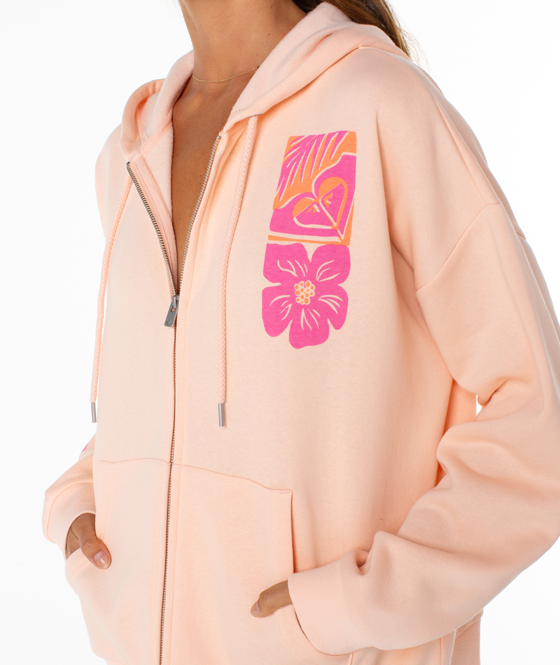 A person wears the Roxy Evening Lineup Hoodie, an everyday essential zip-up in light peach with pink and orange floral and leaf designs on the upper chest. Their hands are in the pockets, set against a white background.