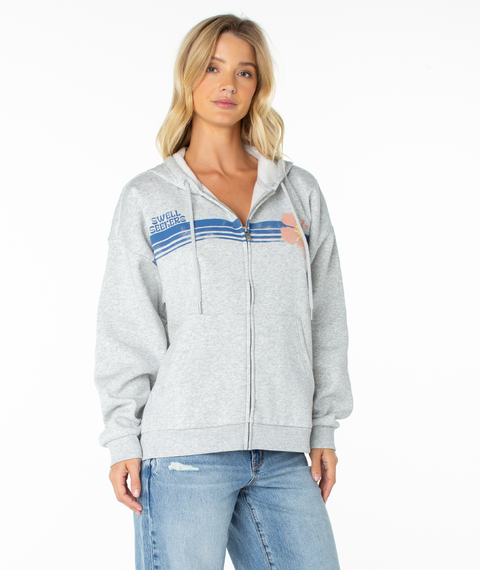 A woman wears the Roxy Sundown Zip Hoodie in Heather Gray Swell Seekers Surf Club, featuring blue stripes and a floral chest graphic, styled with light blue jeans against a plain white background.