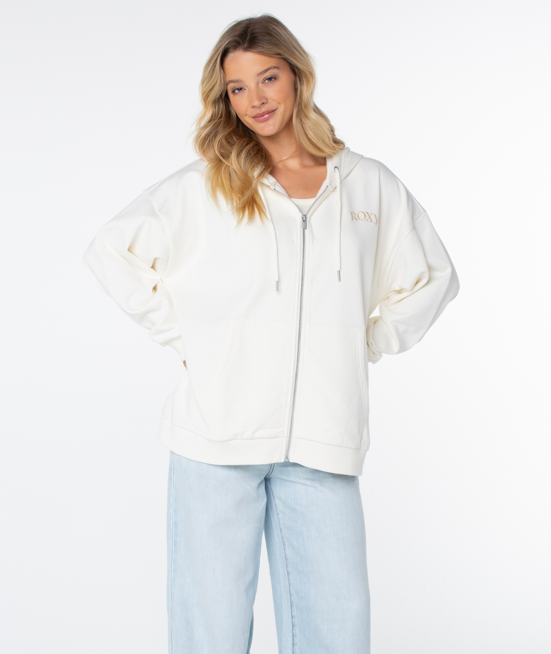 A woman with long blonde hair wears the Roxy Line Up Zip cotton-blend hoodie and light blue jeans, standing with hands on hips against a plain white background.