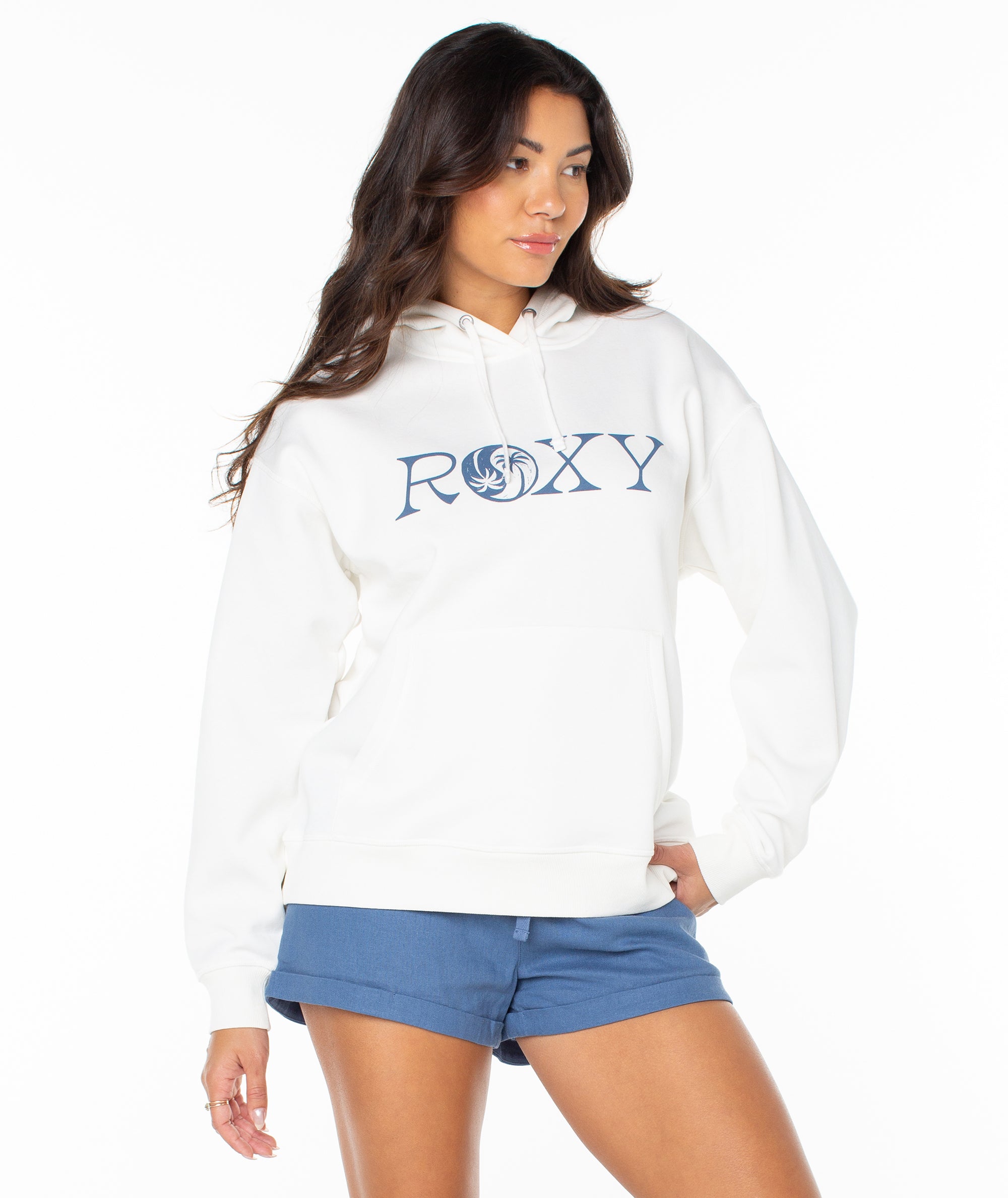 Woman wearing a white hoodie with 'Roxy' logo and blue shorts on a white background