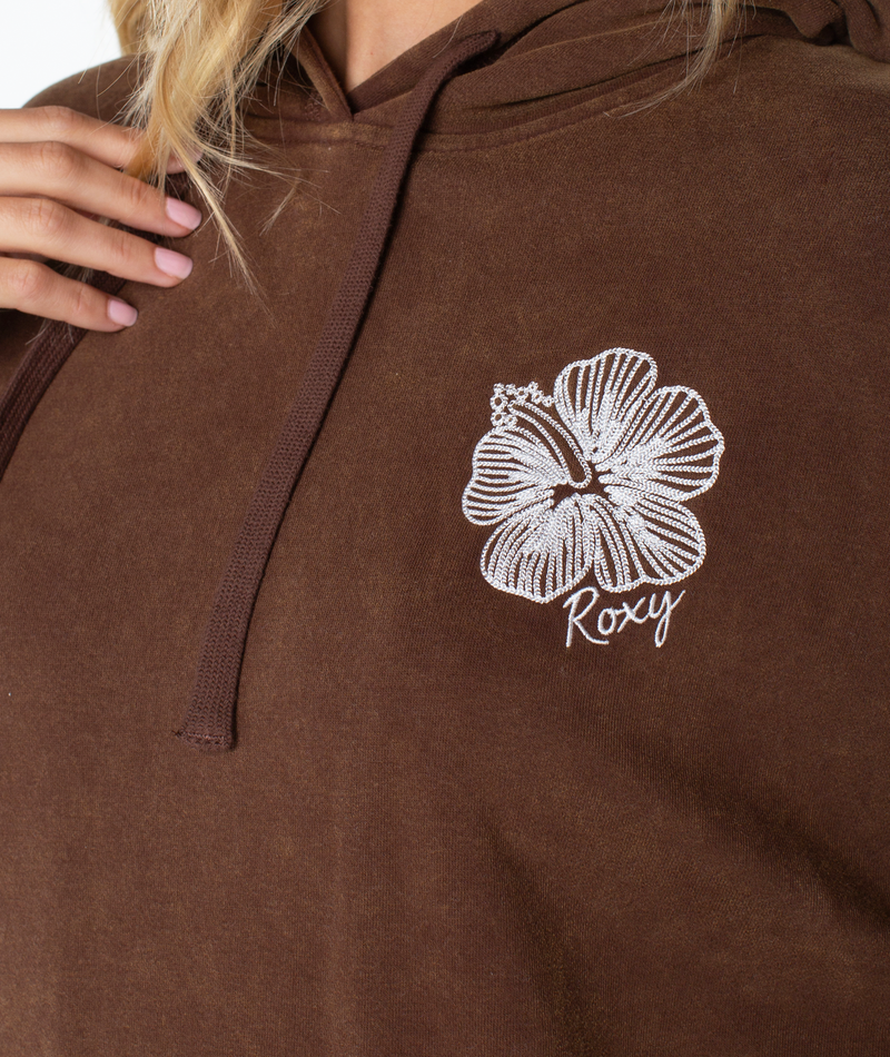 Someone wearing the Wailea Hoodie by Roxy, featuring a slouchy fit, white hibiscus flower, and Roxy embroidered on the chest.