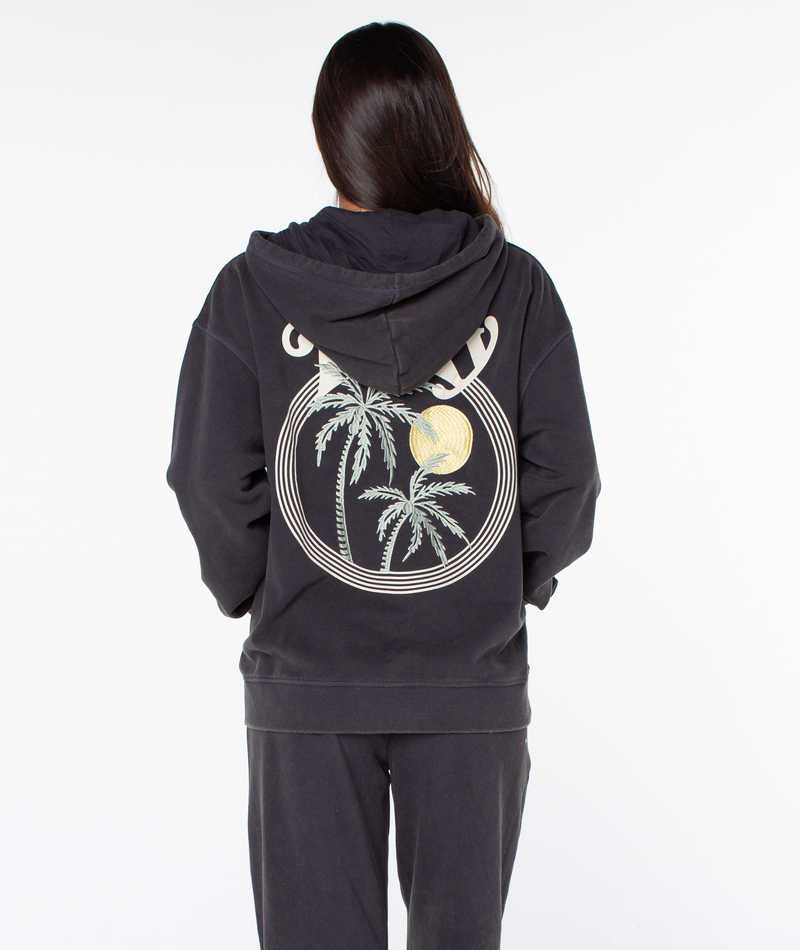 Person with long hair wearing the Roxy Maile Hoodie, which features a palm tree and sun graphic on the back, standing against a white background and facing away from the camera.