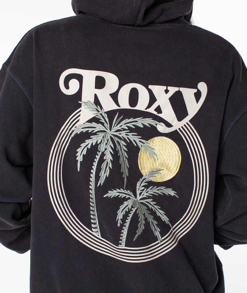 Wearing the Maile Hoodie by Roxy, featuring a relaxed fit and a large Roxy logo with palm trees and a yellow sun graphic on the back, surrounded by concentric circles.