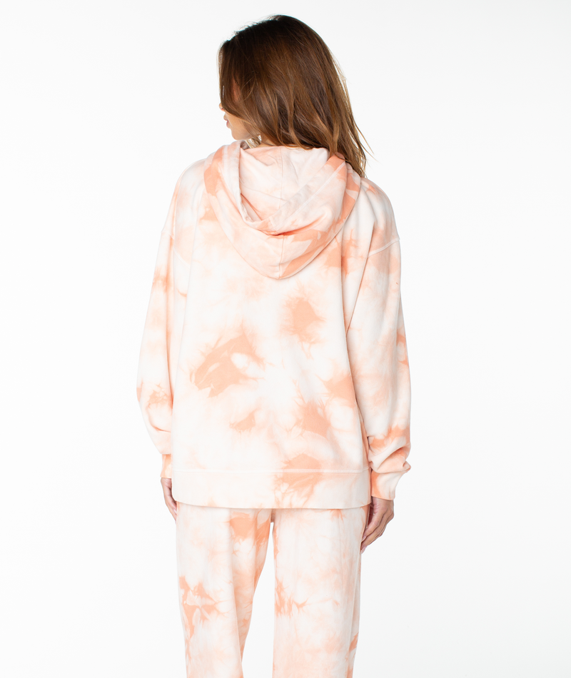 A person stands facing away, wearing the Roxy Maile Tie Dye Hoodie and matching sweatpants—ideal loungewear for relaxing days. Their hair is down, and the background is plain white.