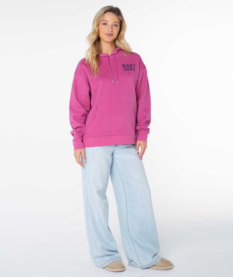 A woman faces forward wearing the Raya Hoodie by Roxy in Red Violet Simple Palm, paired with light blue wide-leg jeans and beige shoes. The background is plain white.