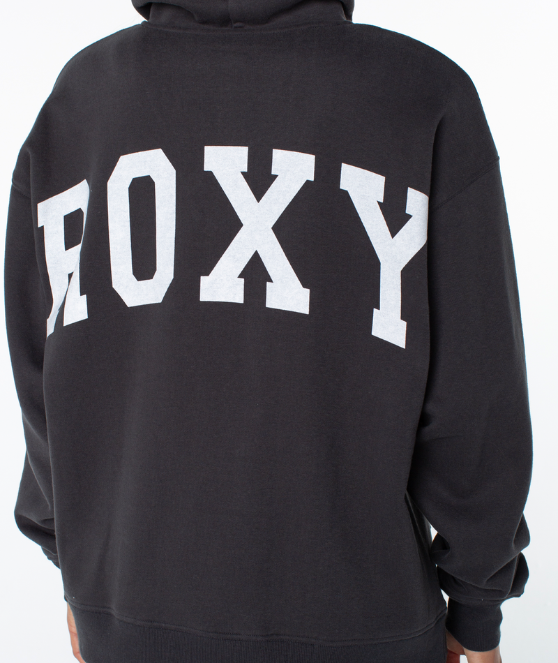 Someone is wearing the Raya Hoodie by Roxy, a black graphic sweatshirt with an oversized fit and ROXY printed in large white letters across the back.