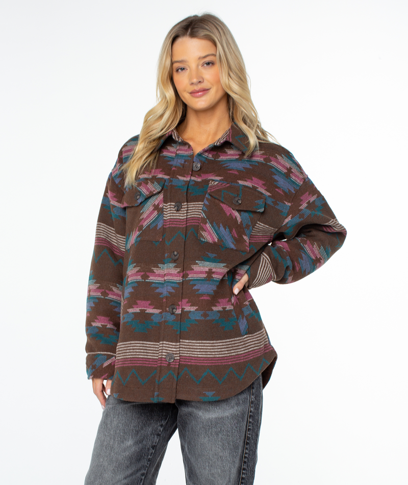 Roxy Overlander Jacket in an oversized button-up style featuring a brown, teal, and magenta geometric pattern, worn with gray jeans.