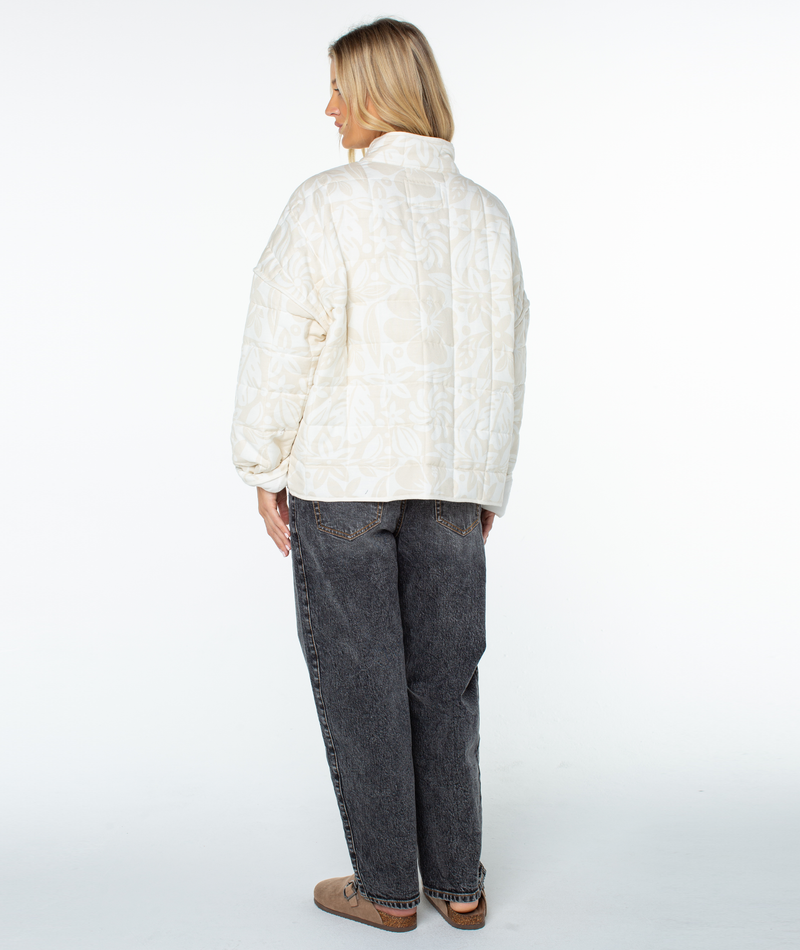 Seen from the back, a person wears a relaxed-fit, cream-colored floral Roxy Solana Jacket, black jeans, and brown slip-on shoes.