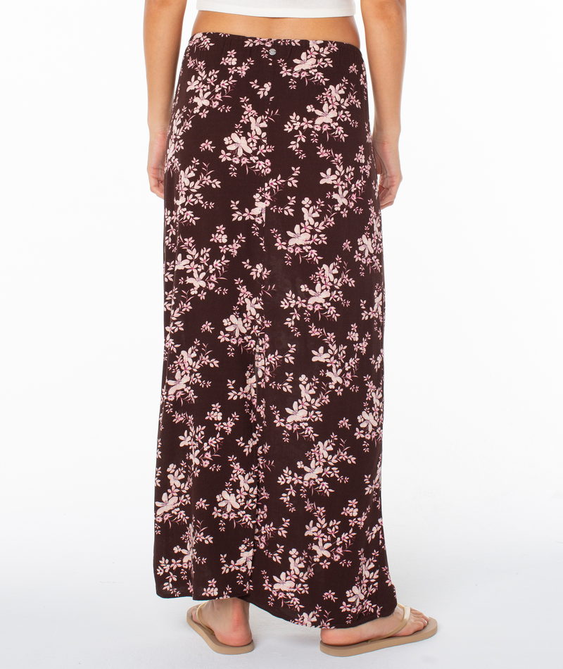 A person wearing the Roxy Iyla Skirt with pink florals and flip-flops, shown from the back against a white background.