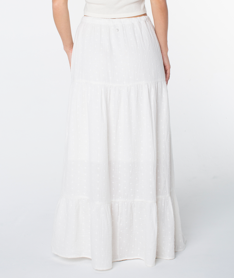 A person wearing the Roxy Side Street Skirt, a long white tiered maxi with a subtle dotted texture, shown from the back against a plain white background.