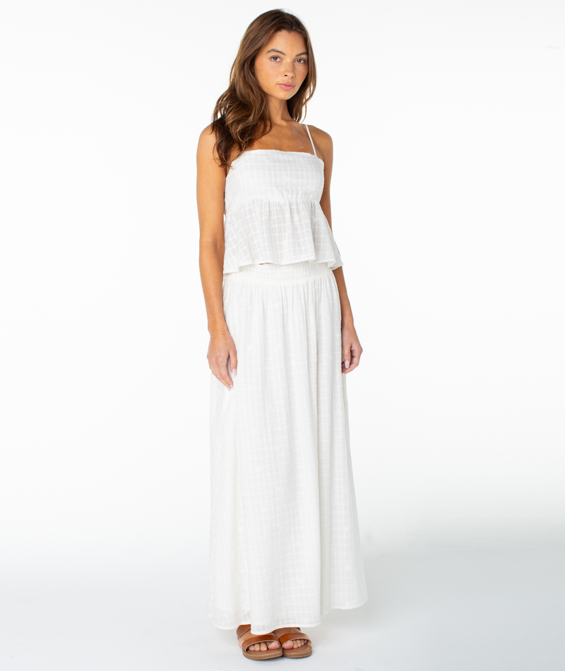 A woman wearing the Roxy Sophie Maxi Skirt in Coconut Milk Solid stands against a plain white background, paired with brown sandals.