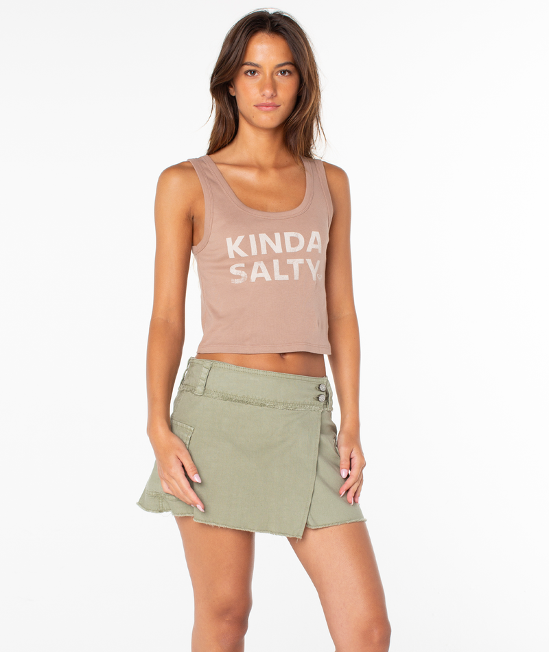 A woman with long brown hair wears the Roxy Kinda Salty Scoop Baby Rib Tank Top in Ginger Snap Kinda Salty and a light green wrap skirt, posing against a white background with a neutral expression.
