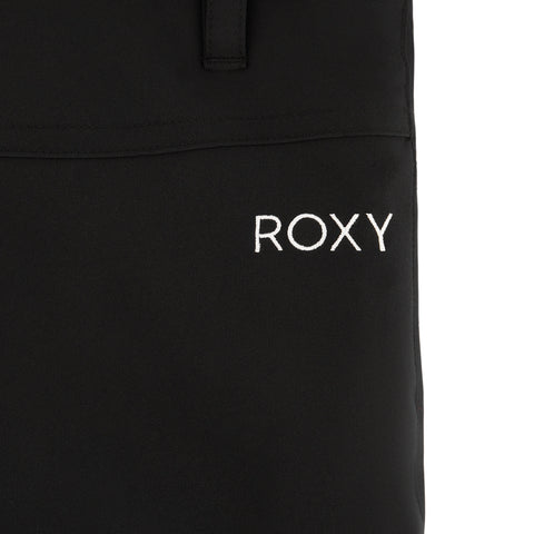 Close-up of black fabric from the Roxy Girls' Backyard Pant with "ROXY" embroidered in white uppercase letters. A seam and part of an adjustable waistband loop or strap are visible at the top of the image.