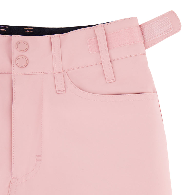Close-up of the waist and upper hip area of Roxy Girls' Backyard Pant in light pink, featuring belt loops, two buttons, a front pocket, and an adjustable Velcro side strap. Stylish girls’ snowboard pants for the slopes.