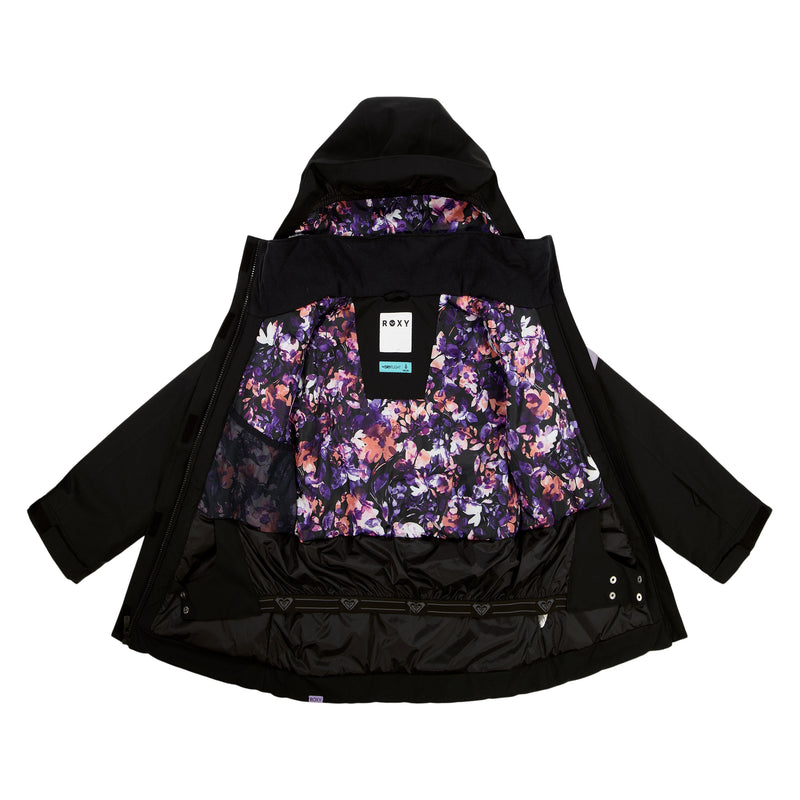 The Roxy Girls' Nollie Jacket in black is displayed open, showing a vibrant purple, pink, and white floral lining. It features a hood, WarmFlight insulation, and a product tag attached to the inner collar.