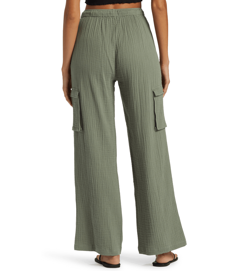 Woman wearing Roxy Precious Cargo Slub Pant in sage green with a loose, wide-leg cargo silhouette and side pockets, viewed from the back against a white background.