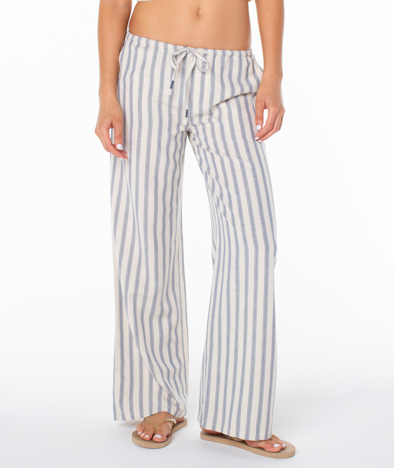 Person wearing Roxy Iyla Pant 2, which are relaxed fit, wide-leg lounge pants with blue vertical stripes and a drawstring waist, paired with flip-flops.