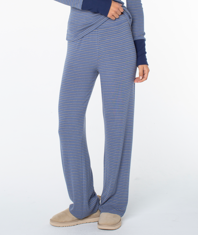 A person wears the Roxy Summer Fling Rib Pant 2 in blue and gray stripes with beige slippers, standing against a plain white background. Only the lower half of the body is shown.