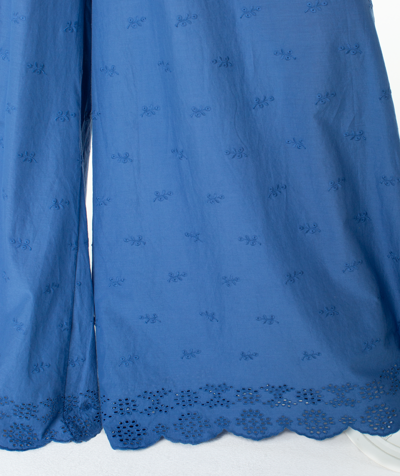 Introducing the Cambria Pant by Roxy: Featuring blue fabric adorned with embroidered floral patterns and a scalloped, cut-out lace hem, this lightweight material drapes softly—ideal for relaxed tailoring or pairing with flowy pieces to create a vibrant statement ensemble.