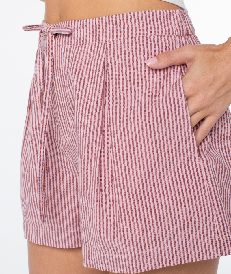 A person wearing the Roxy Mavericks Trouser Short—high-waisted with pink and white vertical stripes, a drawstring waist, and one hand in the pocket—shown from waist to mid-thigh.