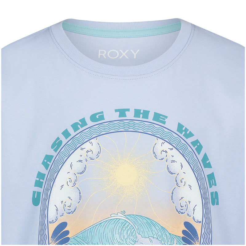 The Roxy Girls' Chasing Waves Oversized Tee is a light blue cotton jersey shirt featuring wave, cloud, and sun graphics with "CHASING THE WAVES" in bold teal letters above the image.