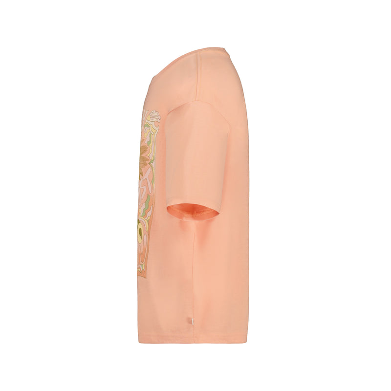 Side view of the Girls' Sunshine Oversized Tee by Roxy, an oversized light peach cotton jersey shirt with a colorful ROXY graphic on the front, shown against a plain white background.
