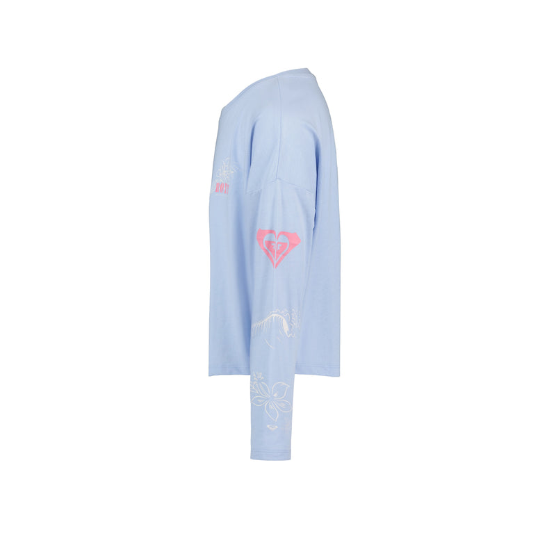 The Roxy Girls' Coastal Journey Long Sleeve Tee is shown from the side in light blue, featuring a pink heart logo on the sleeve, white floral and line accents, subtle pink chest text, all set against a plain white background.