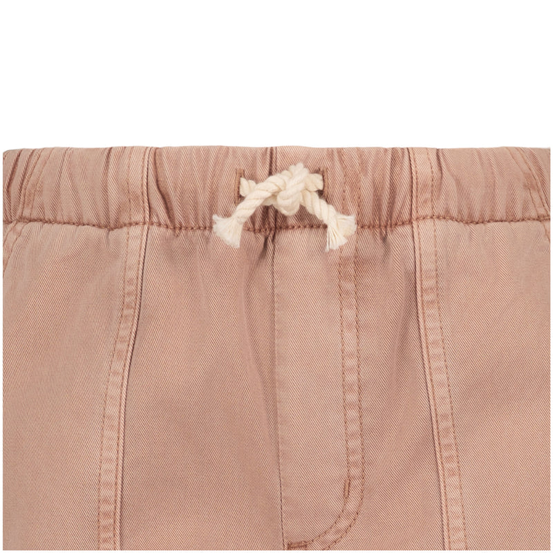Close-up of the waistband on Roxy's Girls' Precious Cargo Pant, featuring a white rope drawstring tied in a knot, visible stitching, and gathered cotton canvas twill fabric in light brown.